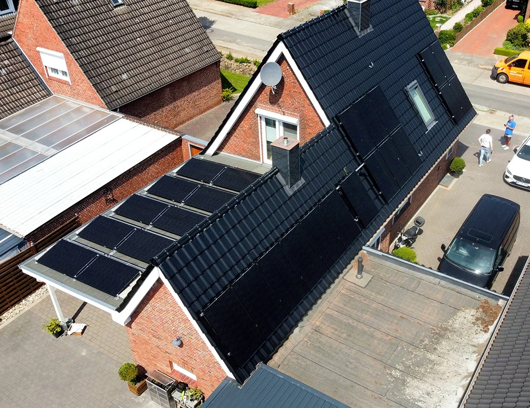 Solarmodule auf dem Steildach und Anbau eines roten Backsteinhauses